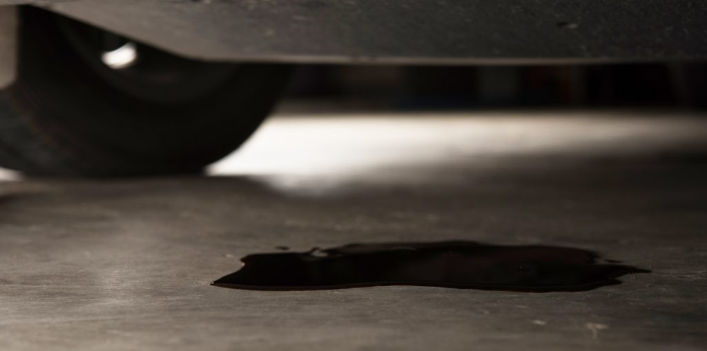 Oil leak or drop from engine of car on concrete floor , check and maintenance auto service